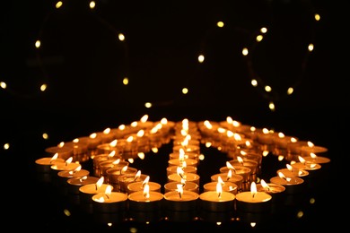 Photo of Many burning candles in darkness. Bokeh effect