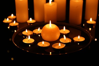 Photo of Group of burning candles on dark surface