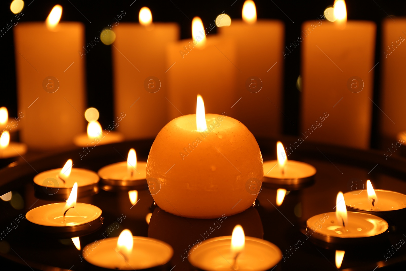 Photo of Many burning candles on dark surface, closeup