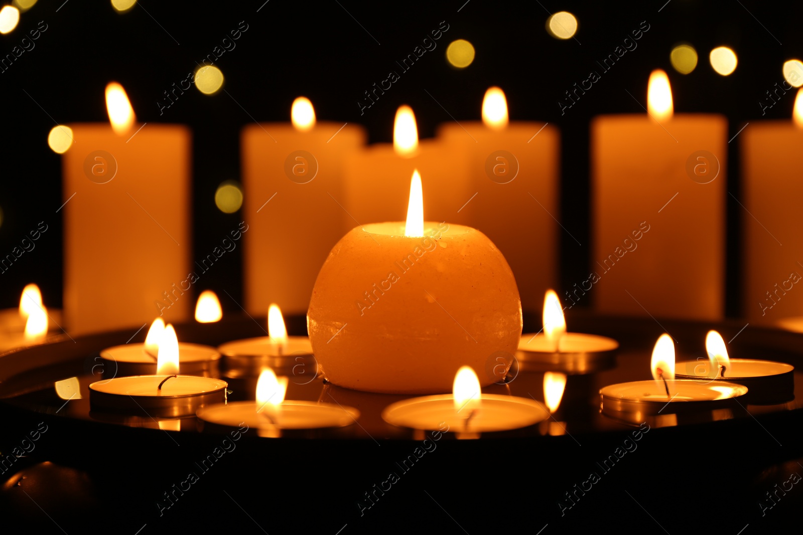 Photo of Many burning candles on dark surface, closeup