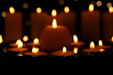 Photo of Many burning candles on dark surface, closeup