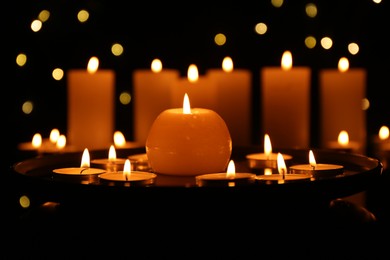 Photo of Many burning candles in darkness, closeup. Bokeh effect