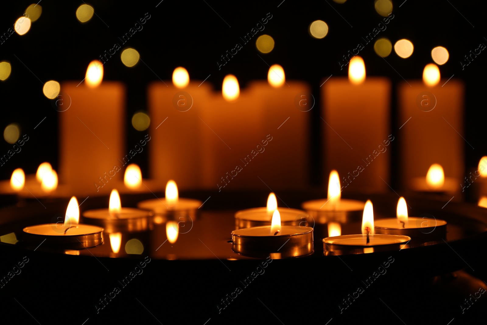 Photo of Many burning candles in darkness, closeup. Bokeh effect