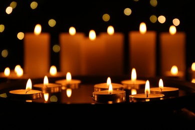 Photo of Many burning candles in darkness, closeup. Bokeh effect