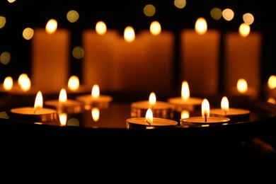 Photo of Many burning candles in darkness, closeup. Bokeh effect