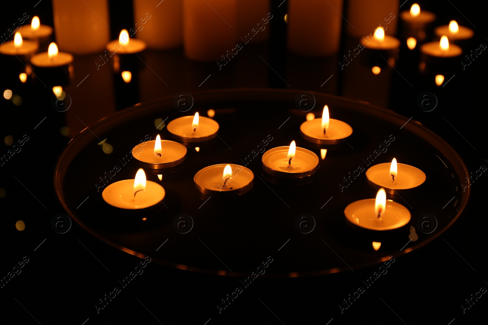 Photo of Group of burning candles on dark surface