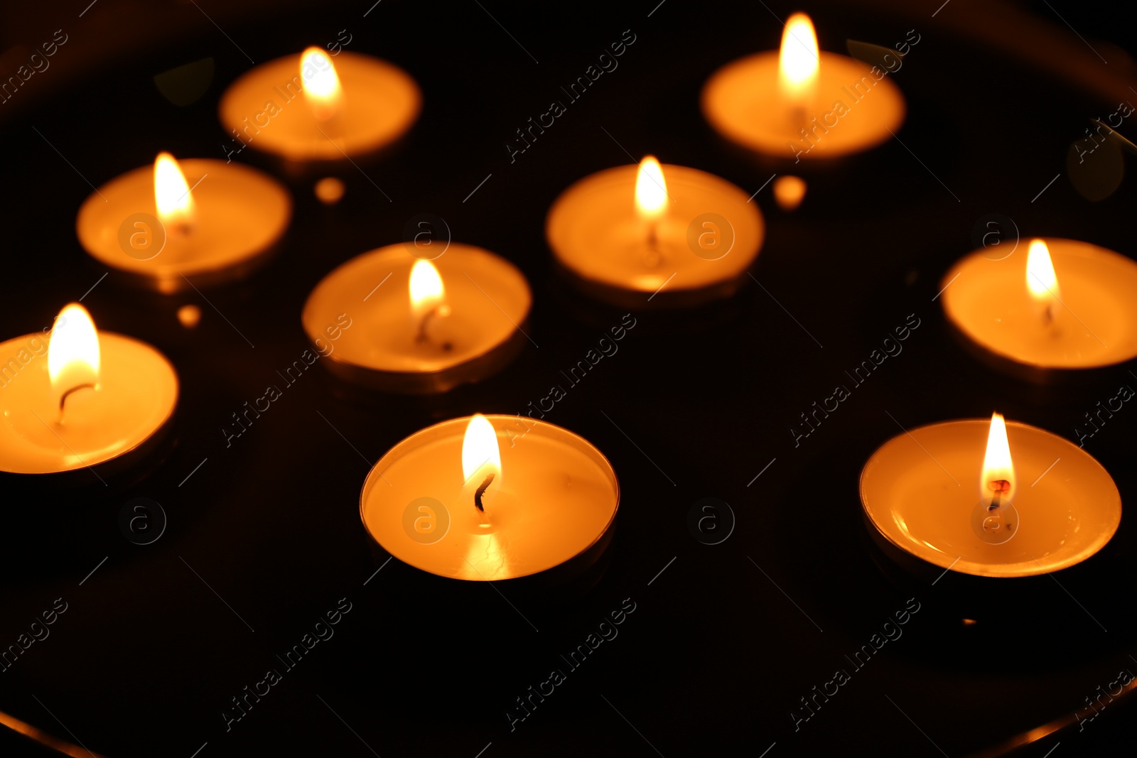 Photo of Many burning candles on dark surface, closeup