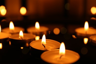 Photo of Many burning candles on dark surface, closeup