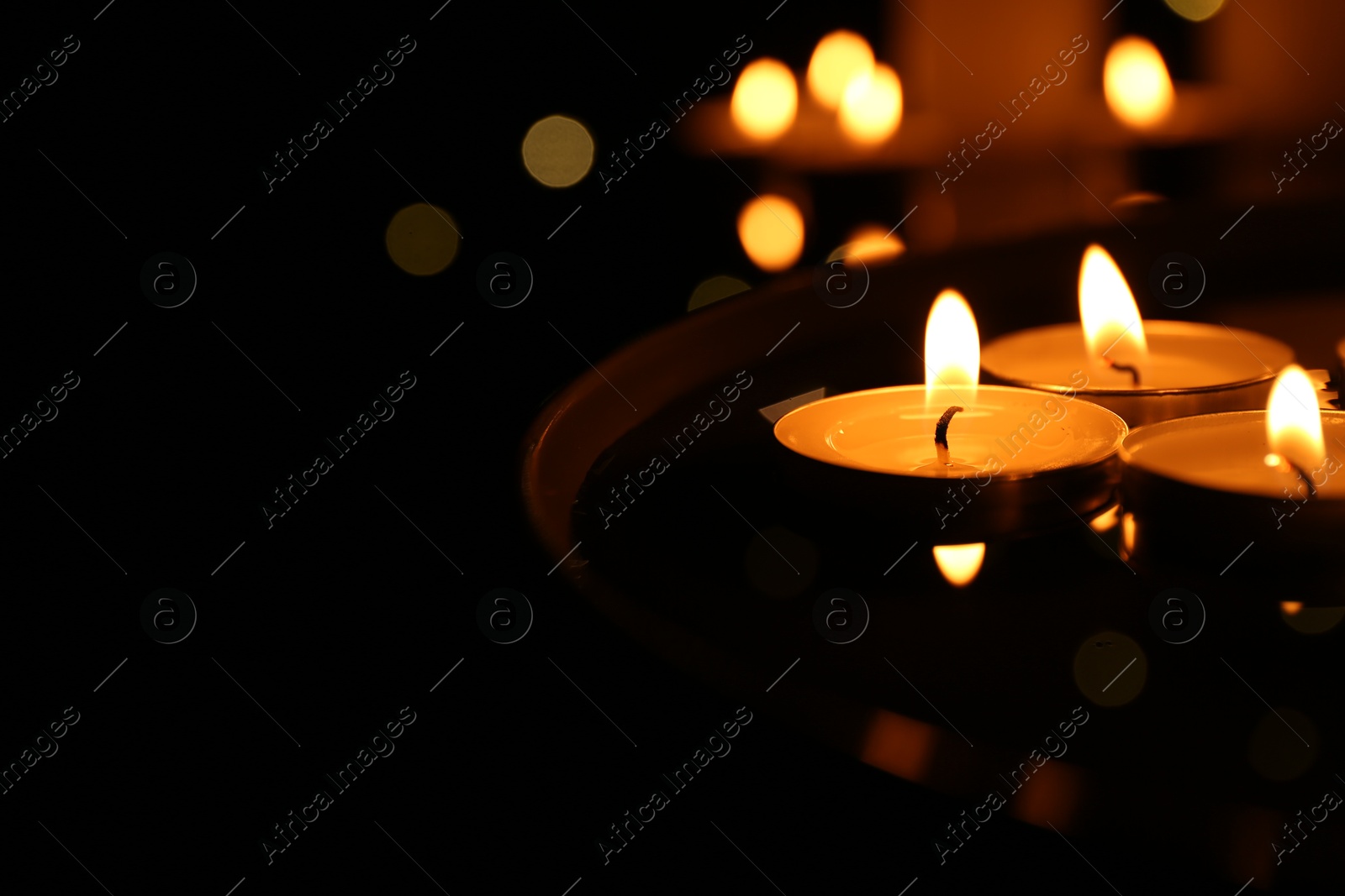 Photo of Burning candles on dark surface, closeup. Space for text