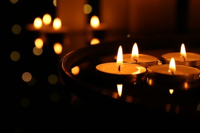 Photo of Many burning candles on dark surface, closeup