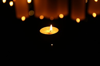 Photo of Burning candle on dark surface, closeup. Bokeh effect