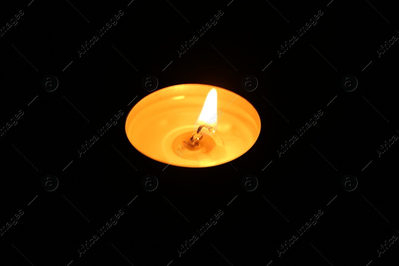 Photo of One burning candle in darkness, closeup view