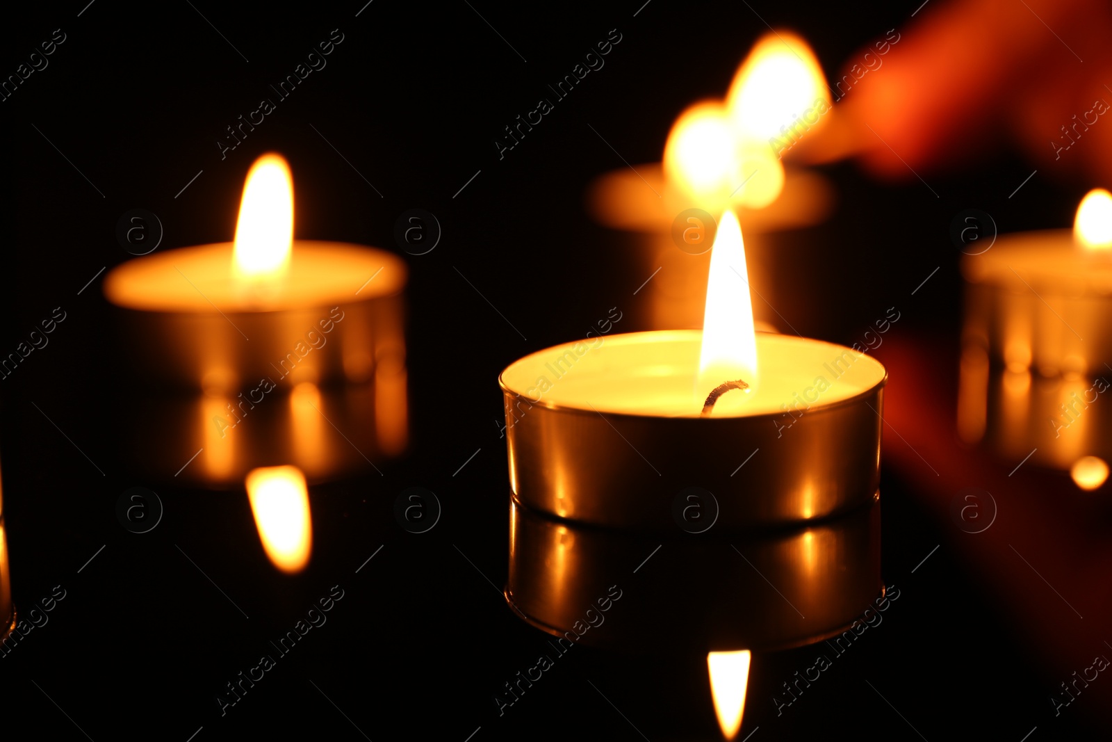 Photo of Burning candles on surface in darkness, closeup