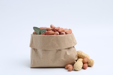 Fresh peanuts in paper bag and unpeeled ones isolated on white