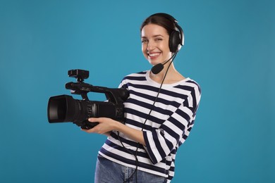 Photo of Happy woman with professional video camera and headset on light blue background