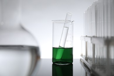 Photo of Laboratory glassware with liquid on mirror surface against light background