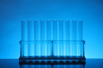 Photo of Test tubes on mirror surface against light blue background. Laboratory glassware