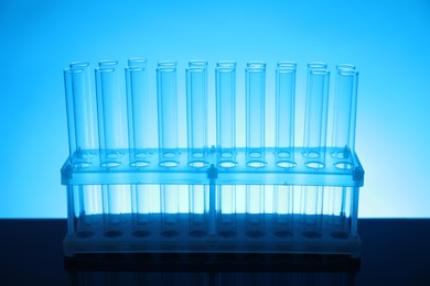 Photo of Test tubes on mirror surface against light blue background. Laboratory glassware