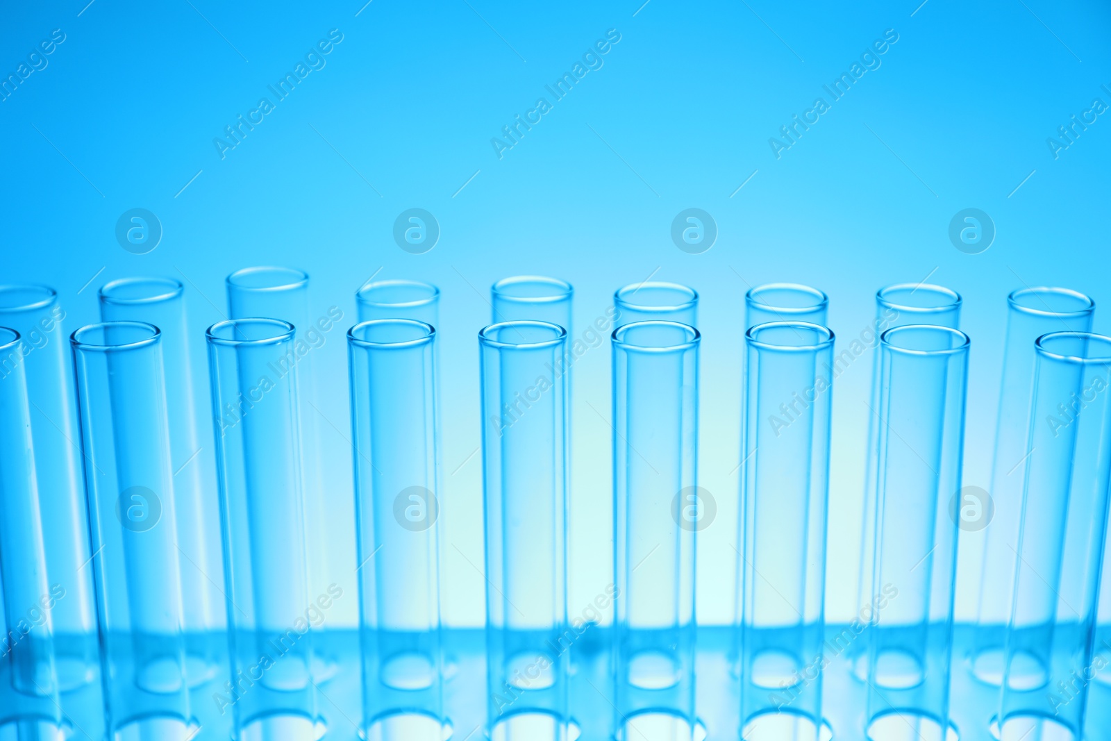 Photo of Test tubes on light blue background, closeup. Laboratory glassware