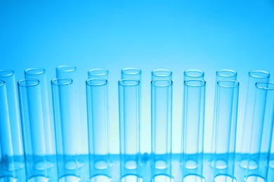 Photo of Test tubes on light blue background, closeup. Laboratory glassware