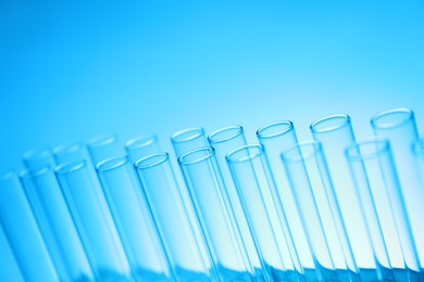 Photo of Test tubes on light blue background, space for text. Laboratory glassware