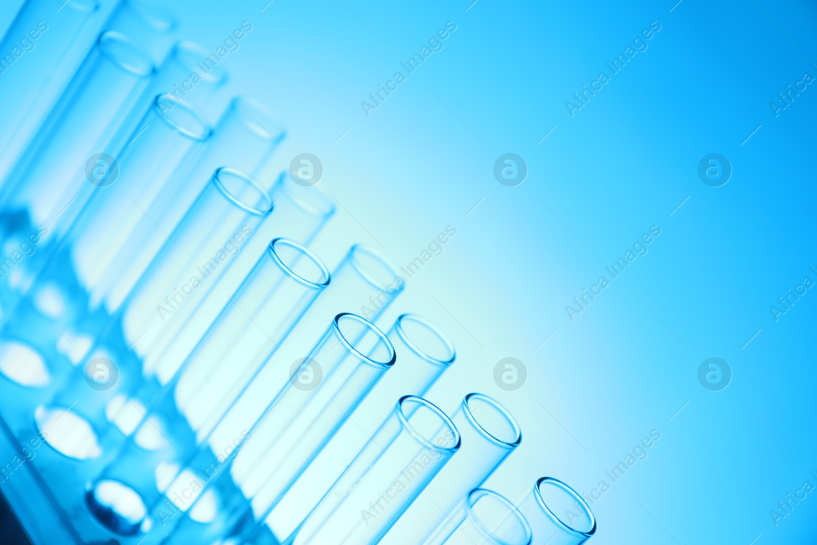 Photo of Test tubes on light blue background, space for text. Laboratory glassware