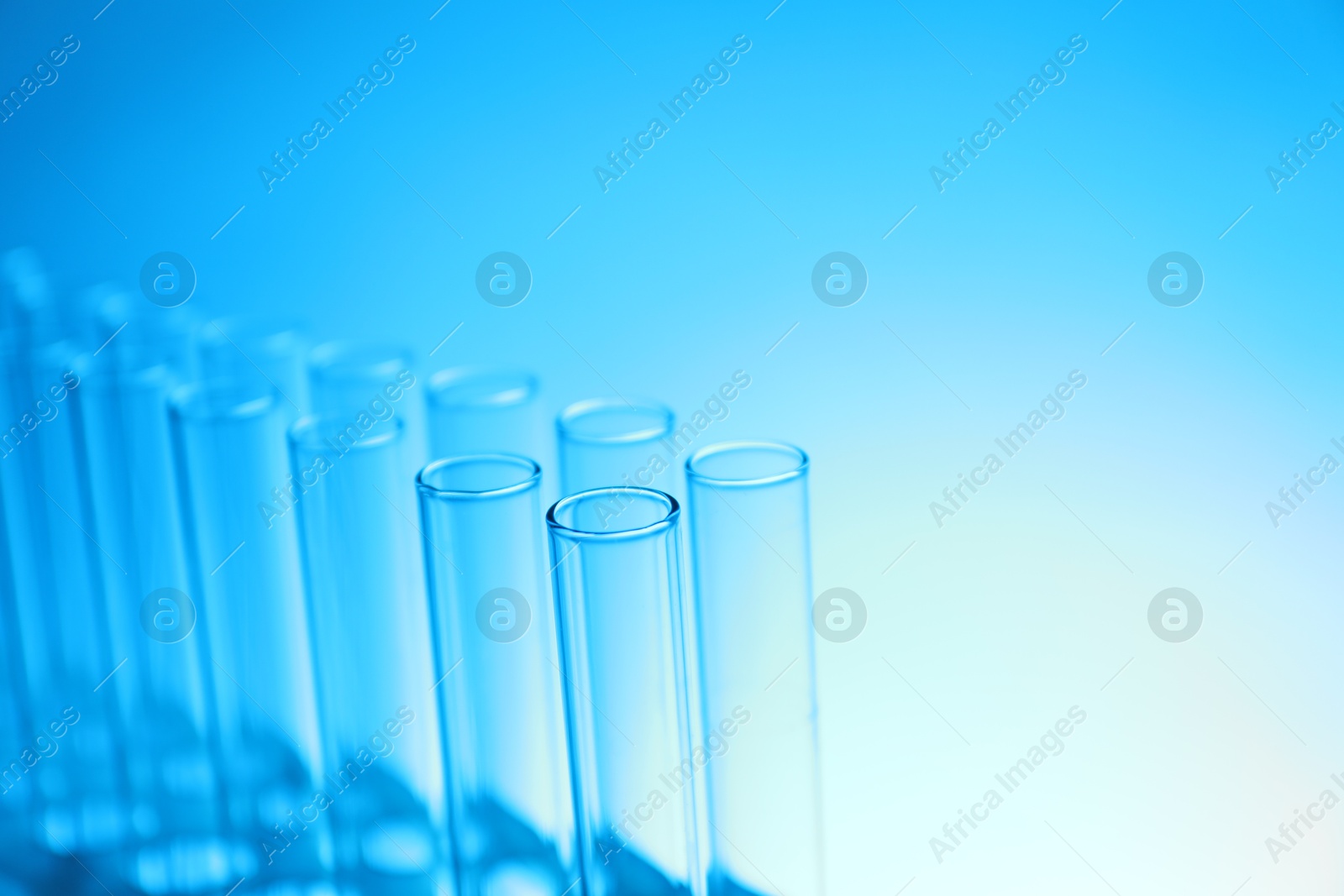 Photo of Test tubes on light blue background, space for text. Laboratory glassware