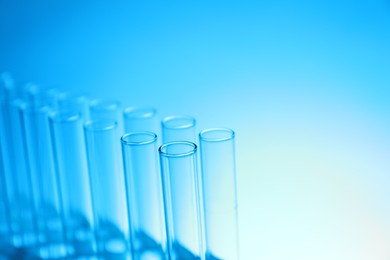 Photo of Test tubes on light blue background, space for text. Laboratory glassware