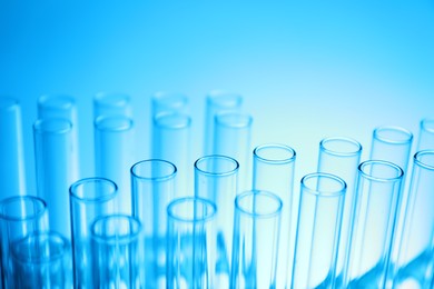 Photo of Test tubes on light blue background, closeup. Laboratory glassware