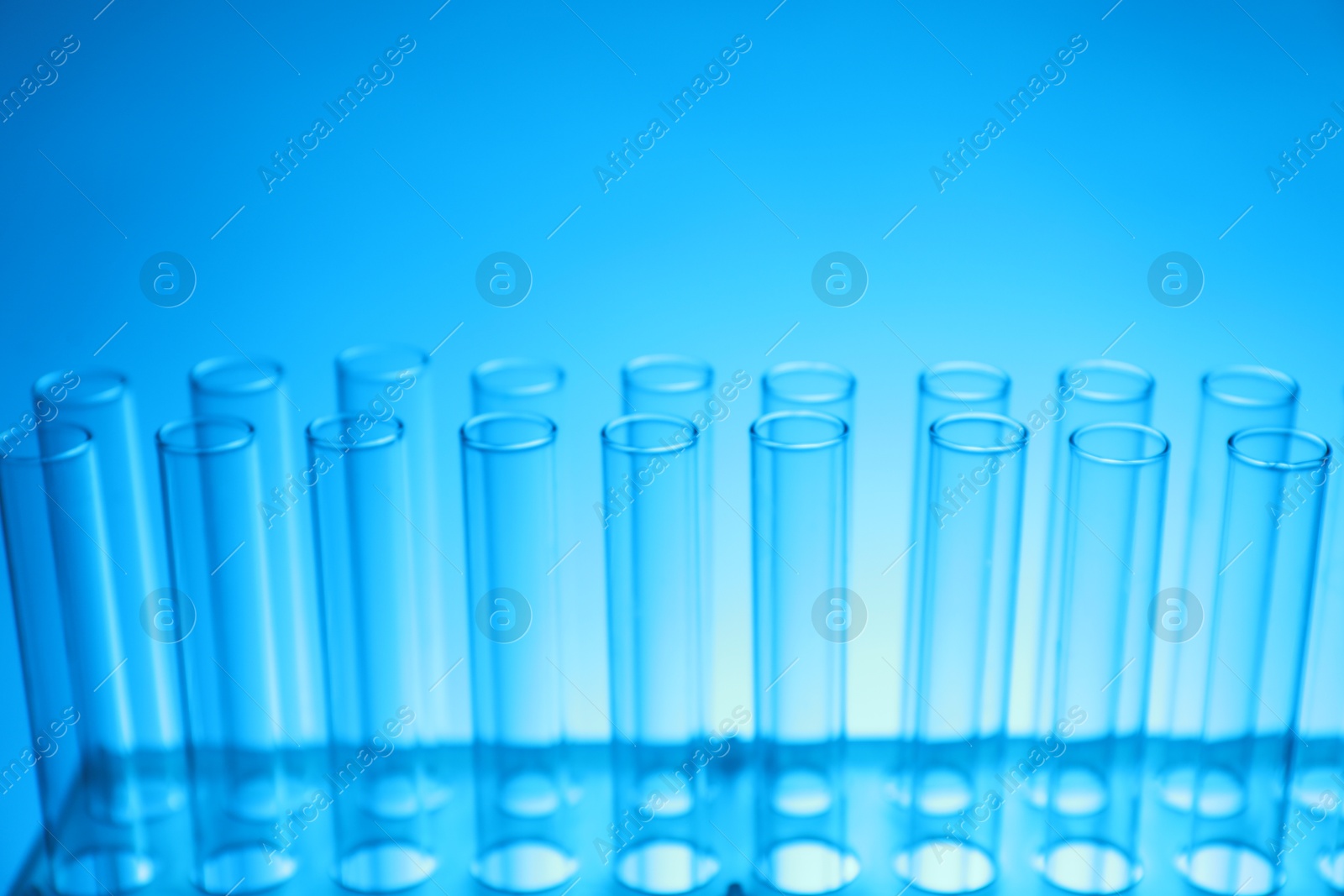 Photo of Test tubes on light blue background, closeup. Laboratory glassware