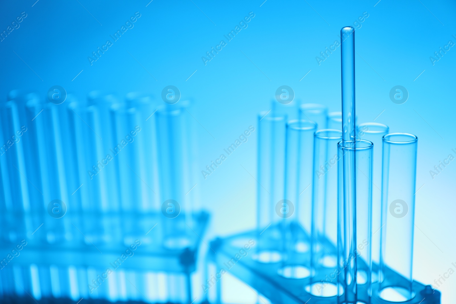 Photo of Test tubes and glass rod on light blue background, closeup. Laboratory glassware