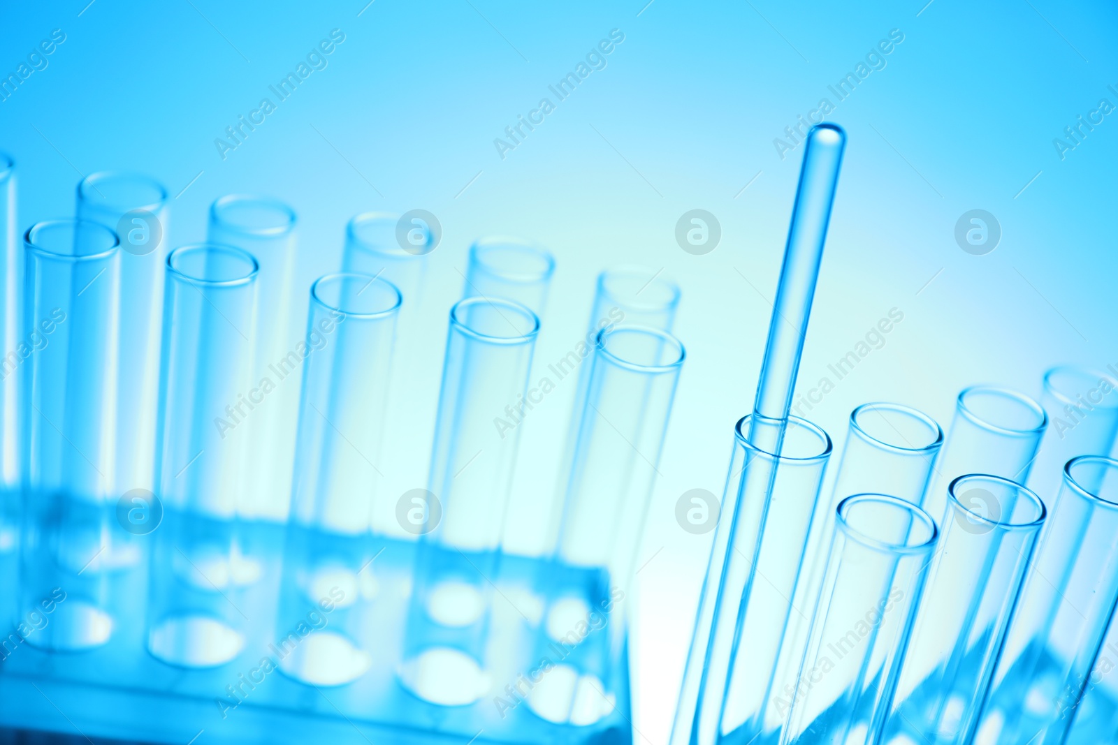 Photo of Test tubes and glass rod on light blue background, closeup. Laboratory glassware