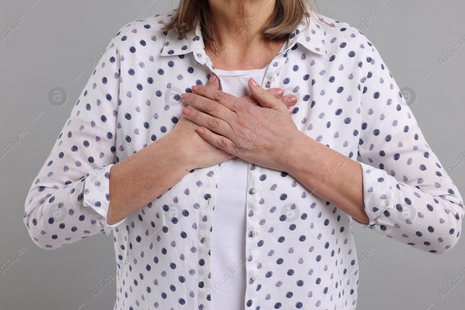 Photo of Heart attack. Senior woman suffering from pain in chest on light grey background, closeup