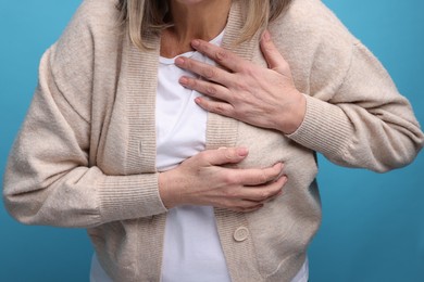 Photo of Heart attack. Senior woman suffering from pain in chest on light blue background, closeup