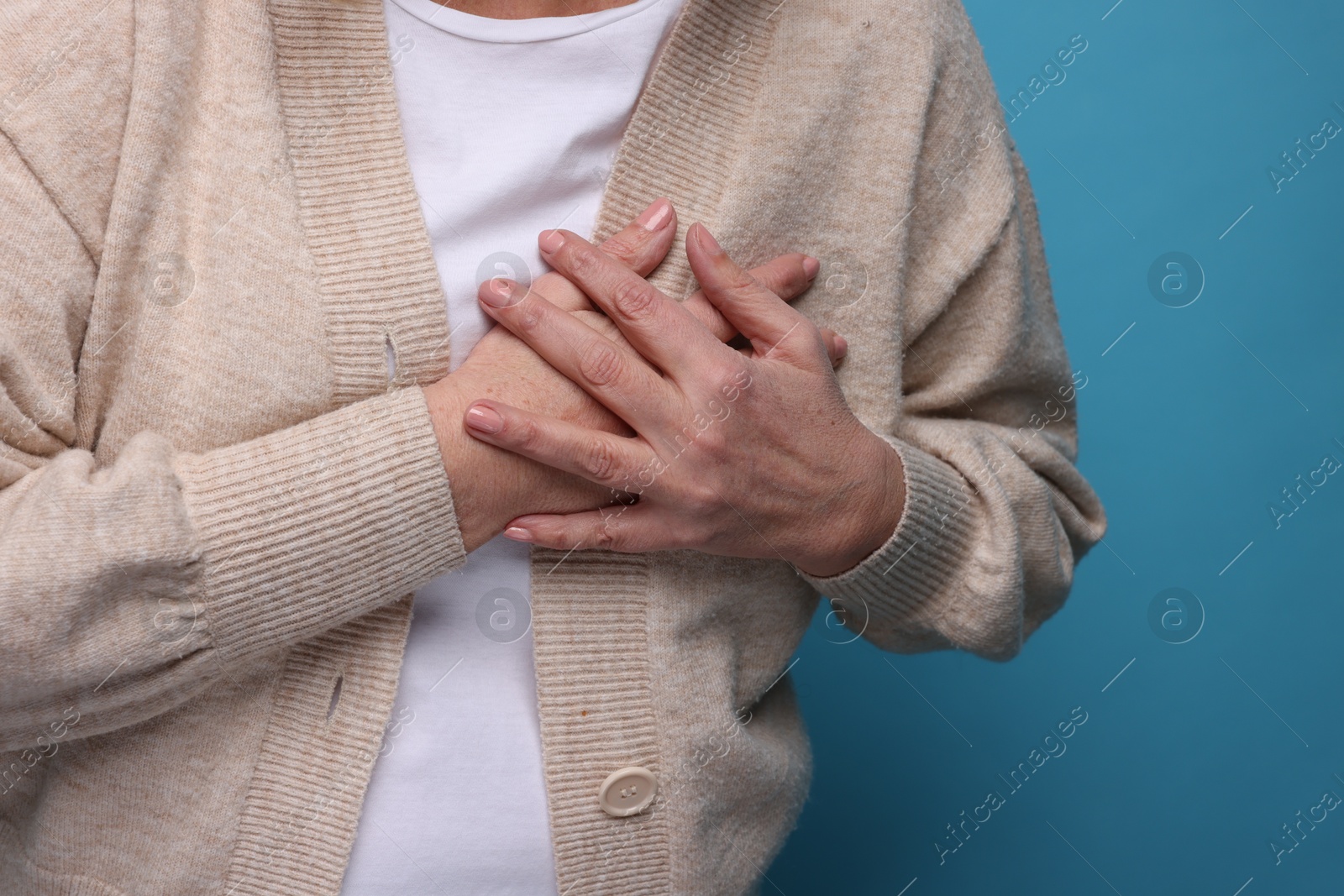 Photo of Heart attack. Senior woman suffering from pain in chest on light blue background, closeup