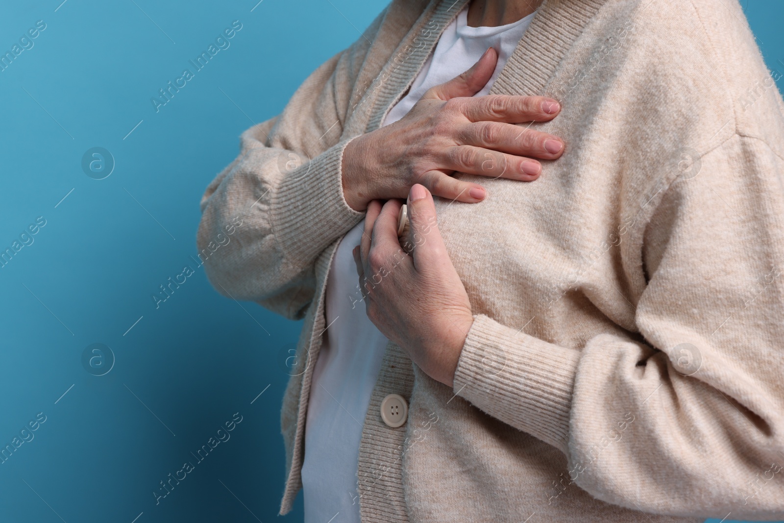 Photo of Heart attack. Senior woman suffering from pain in chest on light blue background, closeup