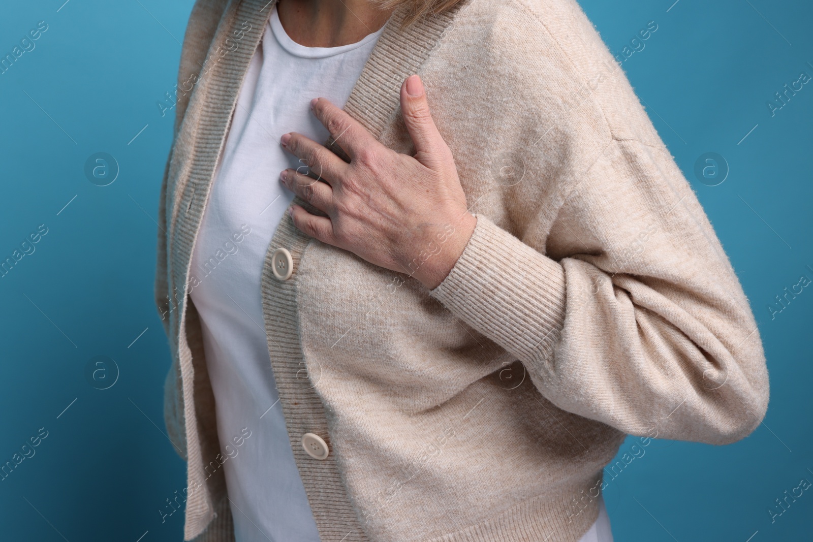 Photo of Heart attack. Senior woman suffering from pain in chest on light blue background, closeup