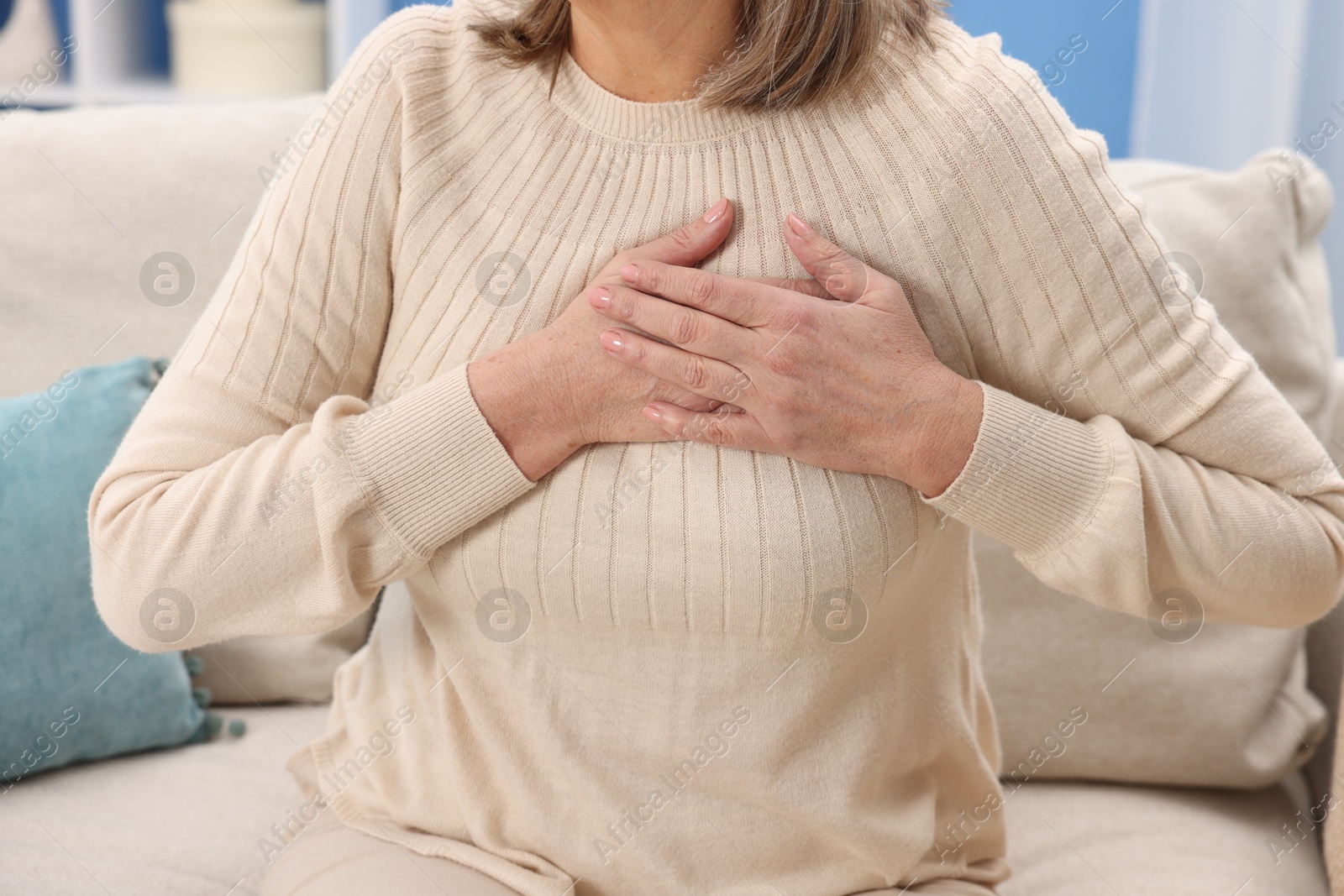 Photo of Heart attack. Senior woman suffering from pain in chest indoors, closeup