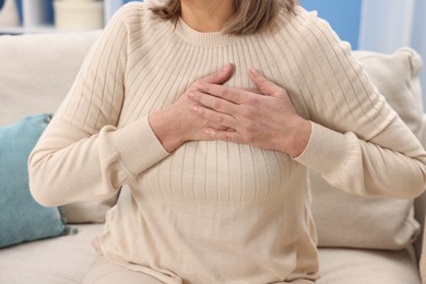 Photo of Heart attack. Senior woman suffering from pain in chest indoors, closeup