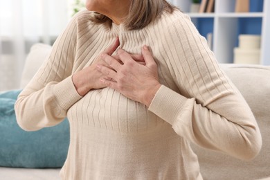 Photo of Heart attack. Senior woman suffering from pain in chest indoors, closeup