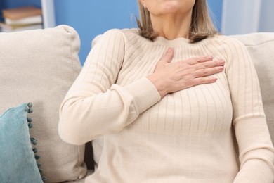 Photo of Heart attack. Senior woman suffering from pain in chest indoors, closeup