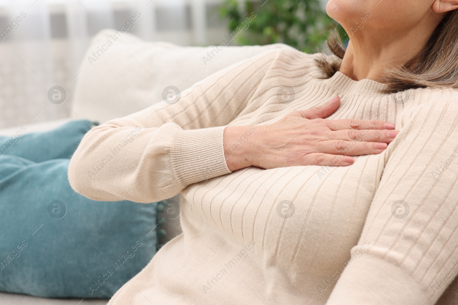 Photo of Heart attack. Senior woman suffering from pain in chest indoors, closeup