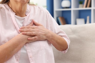 Photo of Heart attack. Senior woman suffering from pain in chest indoors, closeup