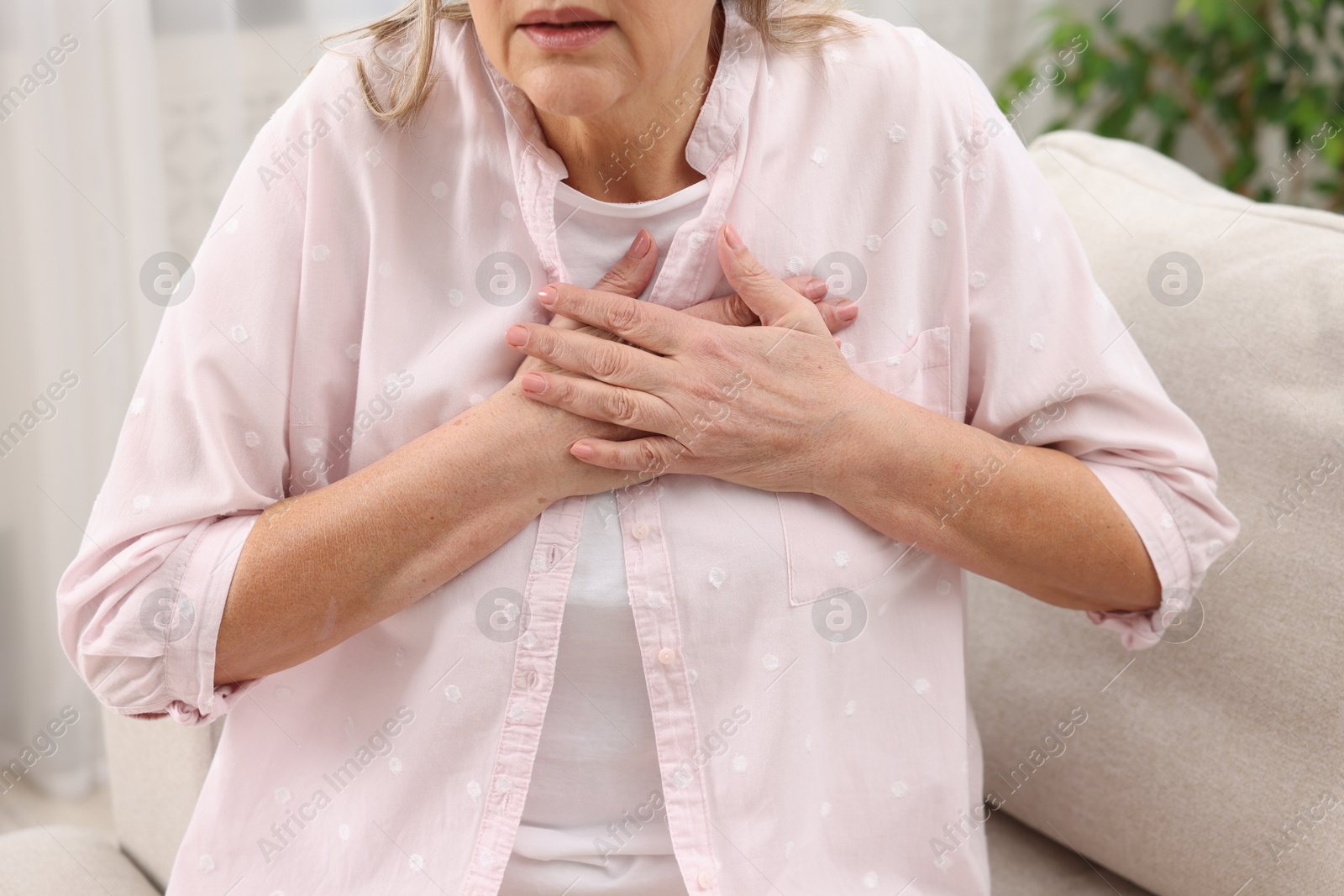 Photo of Heart attack. Senior woman suffering from pain in chest indoors, closeup