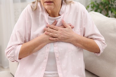 Heart attack. Senior woman suffering from pain in chest indoors, closeup