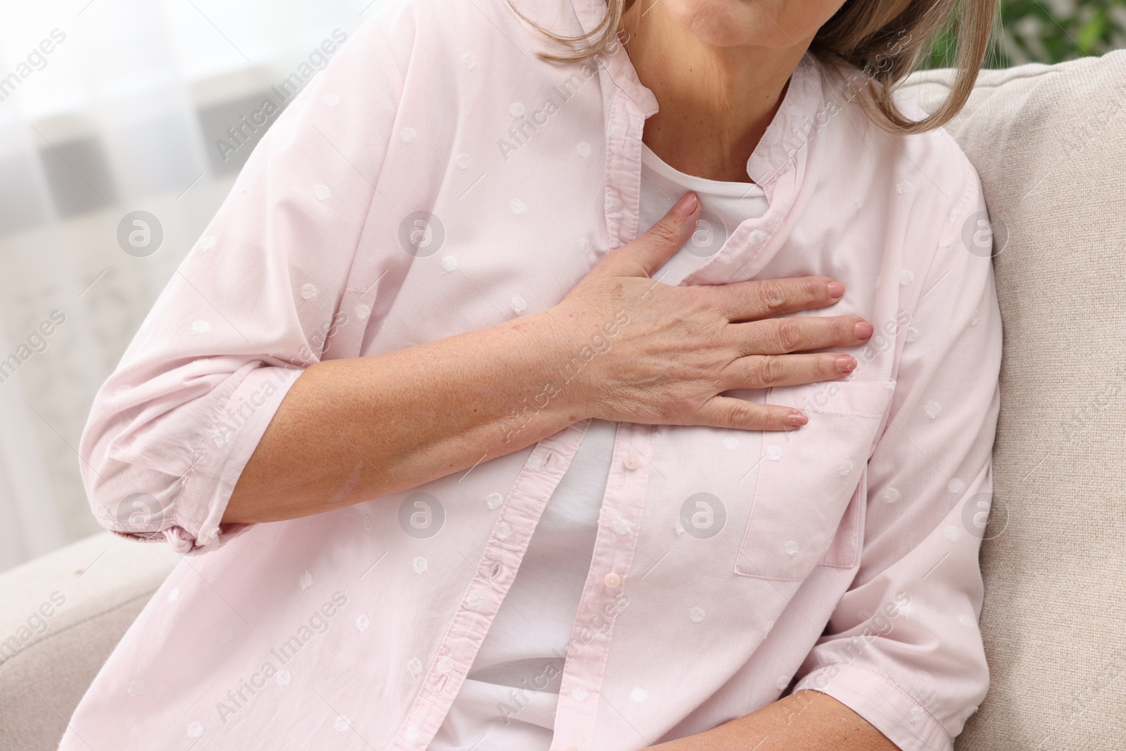 Photo of Heart attack. Senior woman suffering from pain in chest indoors, closeup