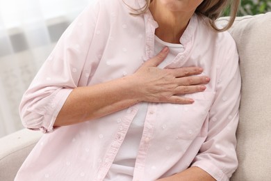 Photo of Heart attack. Senior woman suffering from pain in chest indoors, closeup