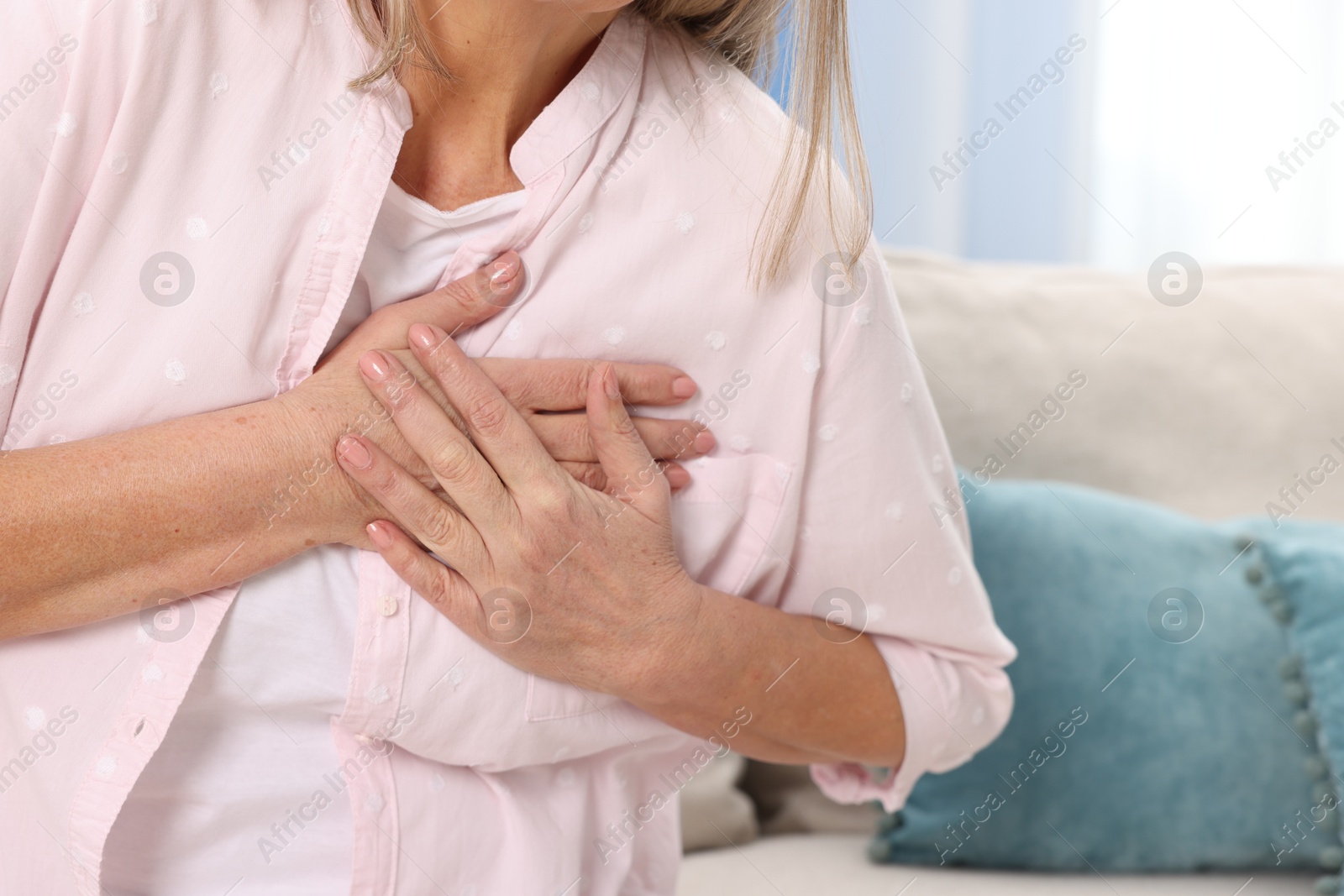 Photo of Heart attack. Senior woman suffering from pain in chest indoors, closeup