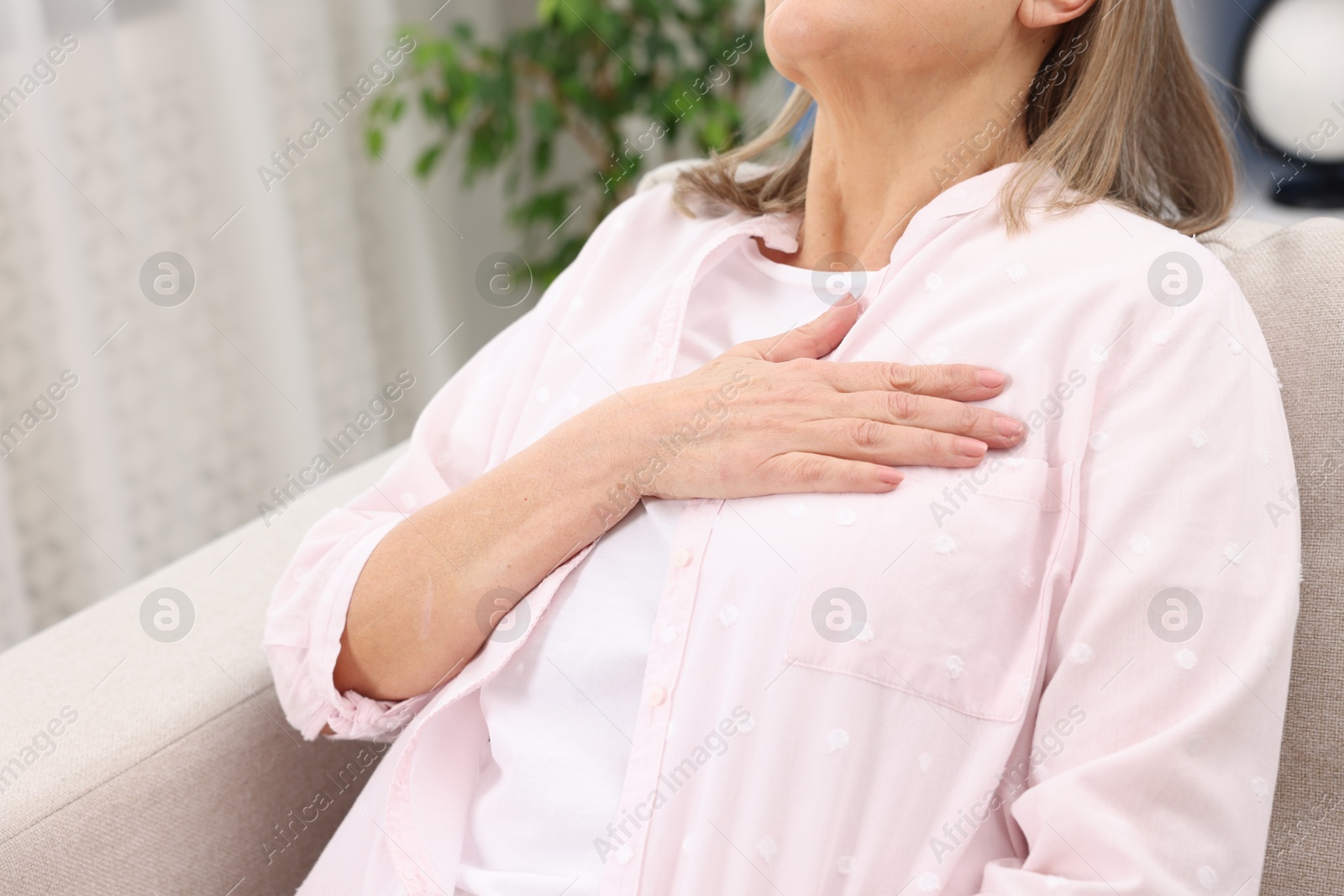 Photo of Heart attack. Senior woman suffering from pain in chest indoors, closeup