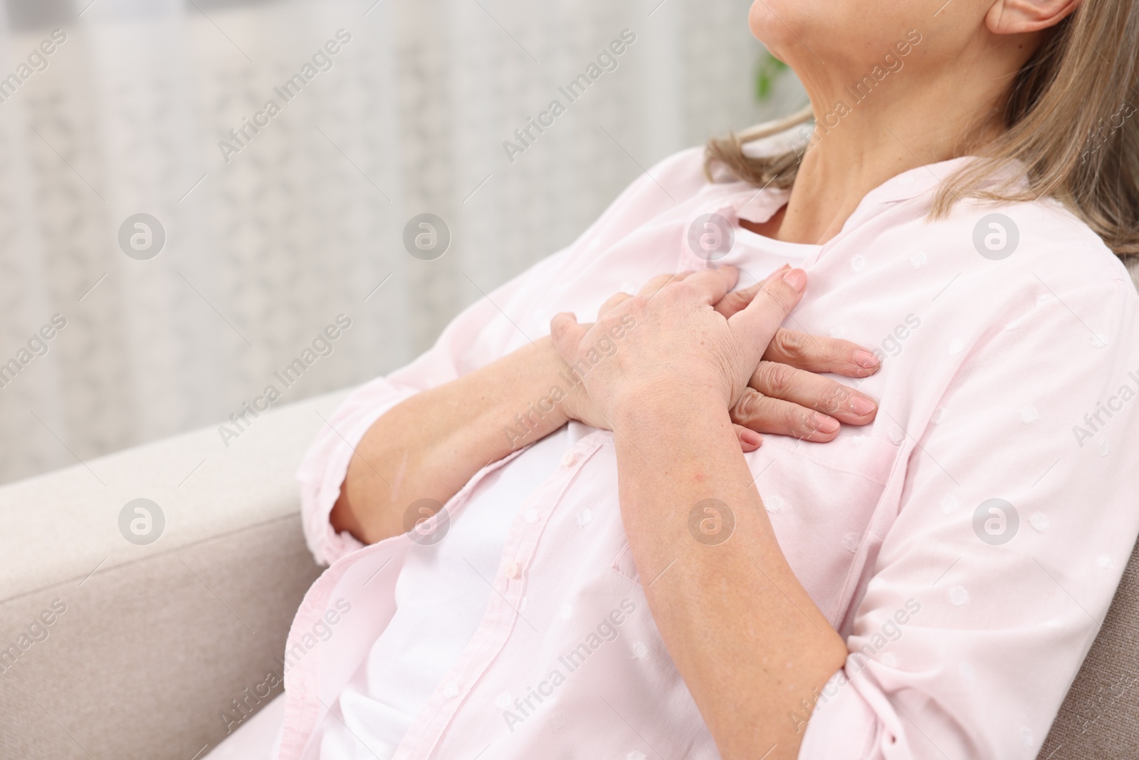 Photo of Heart attack. Senior woman suffering from pain in chest indoors, closeup